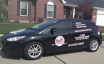 A black car parked in front of a house.